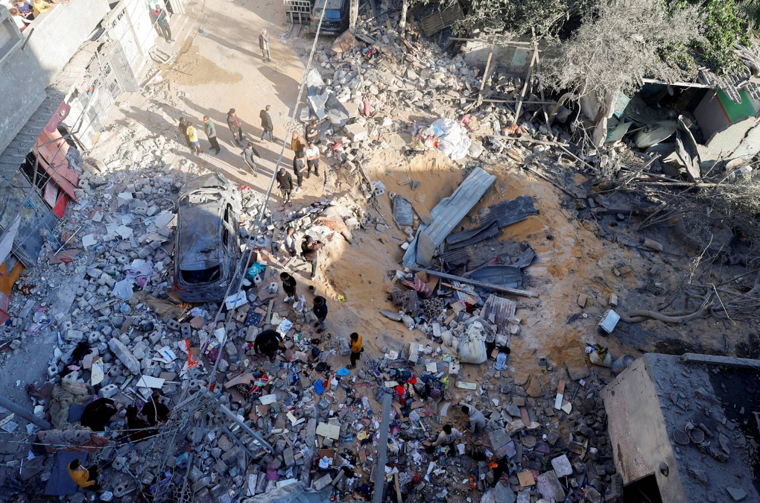 فلسطينيون يتفقدون موقع غارة إسرائيلية على منزل في رفح بجنوب قطاع غزة (رويترز)