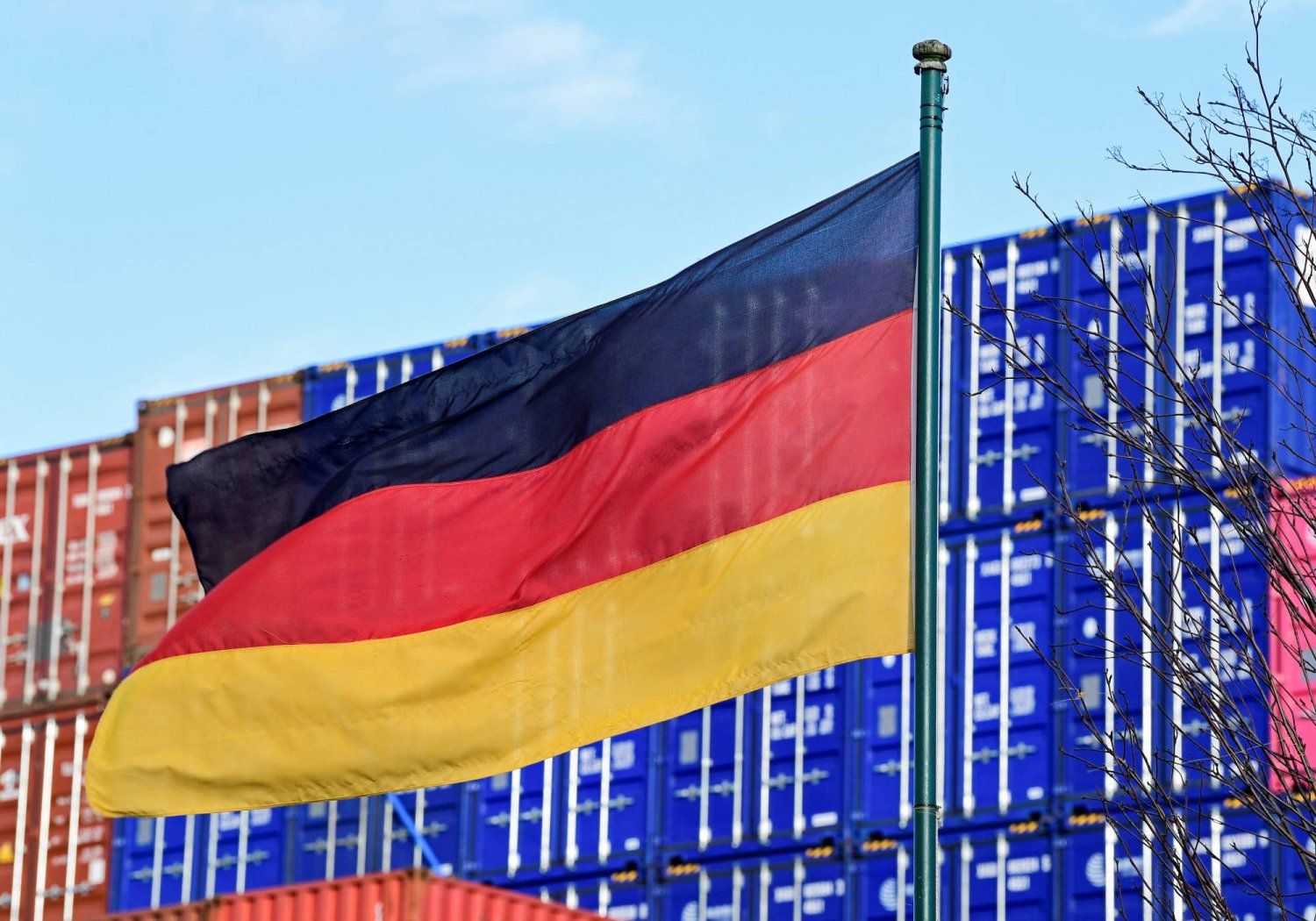 علم ألمانيا يرفرف أمام عدد من الحاويات في ميناء هامبورغ (رويترز)