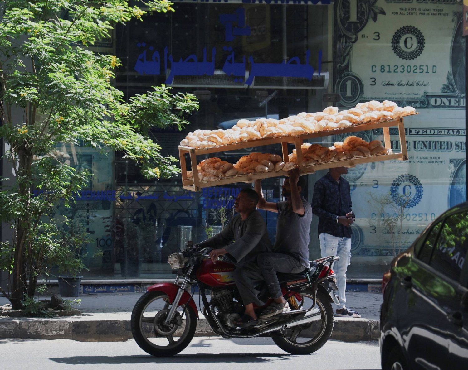 رجل ينقل طاولة من الخبز في أحد شوارع وسط العاصمة المصرية القاهرة (رويترز)