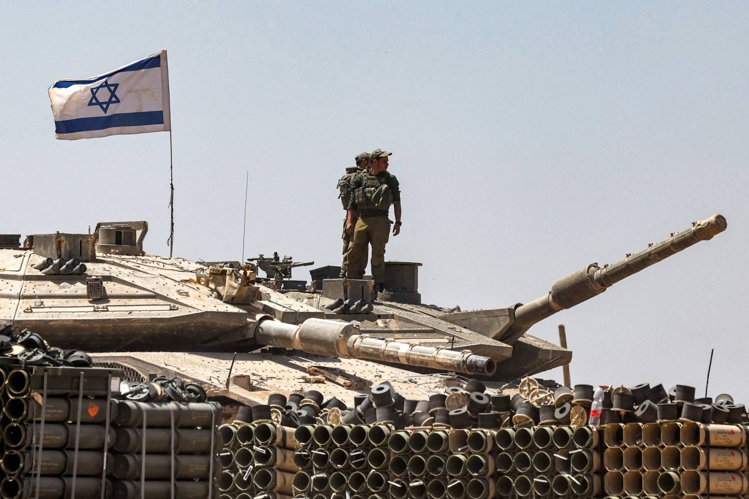 جنود من الجيش الإسرائيلي يقفون فوق برج دبابة متمركزة في جنوب إسرائيل بالقرب من الحدود مع قطاع غزة (أ.ف.ب)