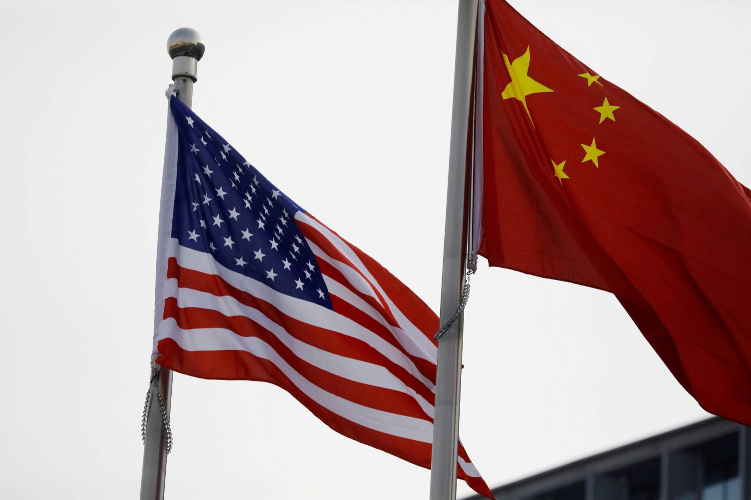 علما الصين والولايات المتحدة يرفرفان خارج مبنى شركة في شنغهاي بالصين في 14 أبريل 2021 (رويترز)