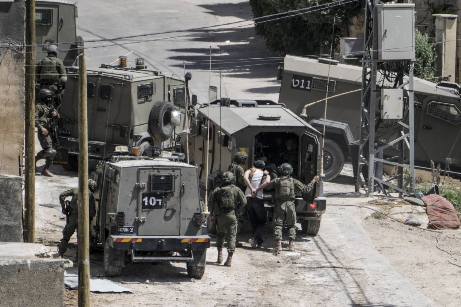 جنود إسرائيليون يعتقلون فلسطينياً خلال مداهمة في قرية دير الغصون بالضفة الغربية (أ.ب)