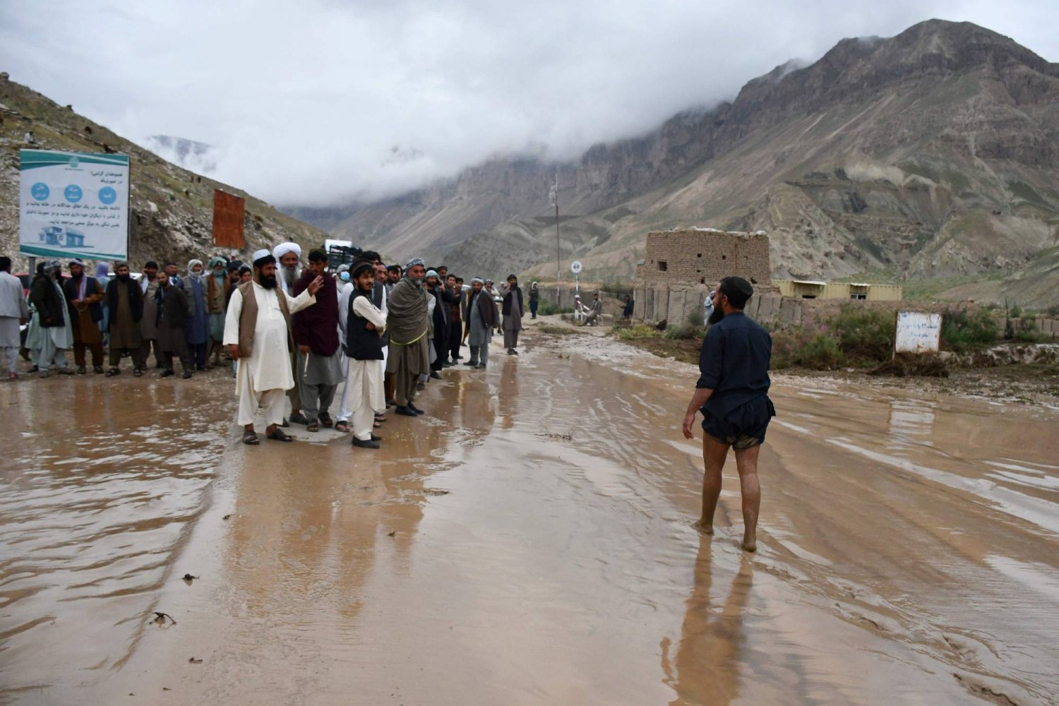 أفغان يقفون وسط الوحول في منطقة فيروز ناخشير بين سامنغان ومزار شريف (أ.ف.ب)