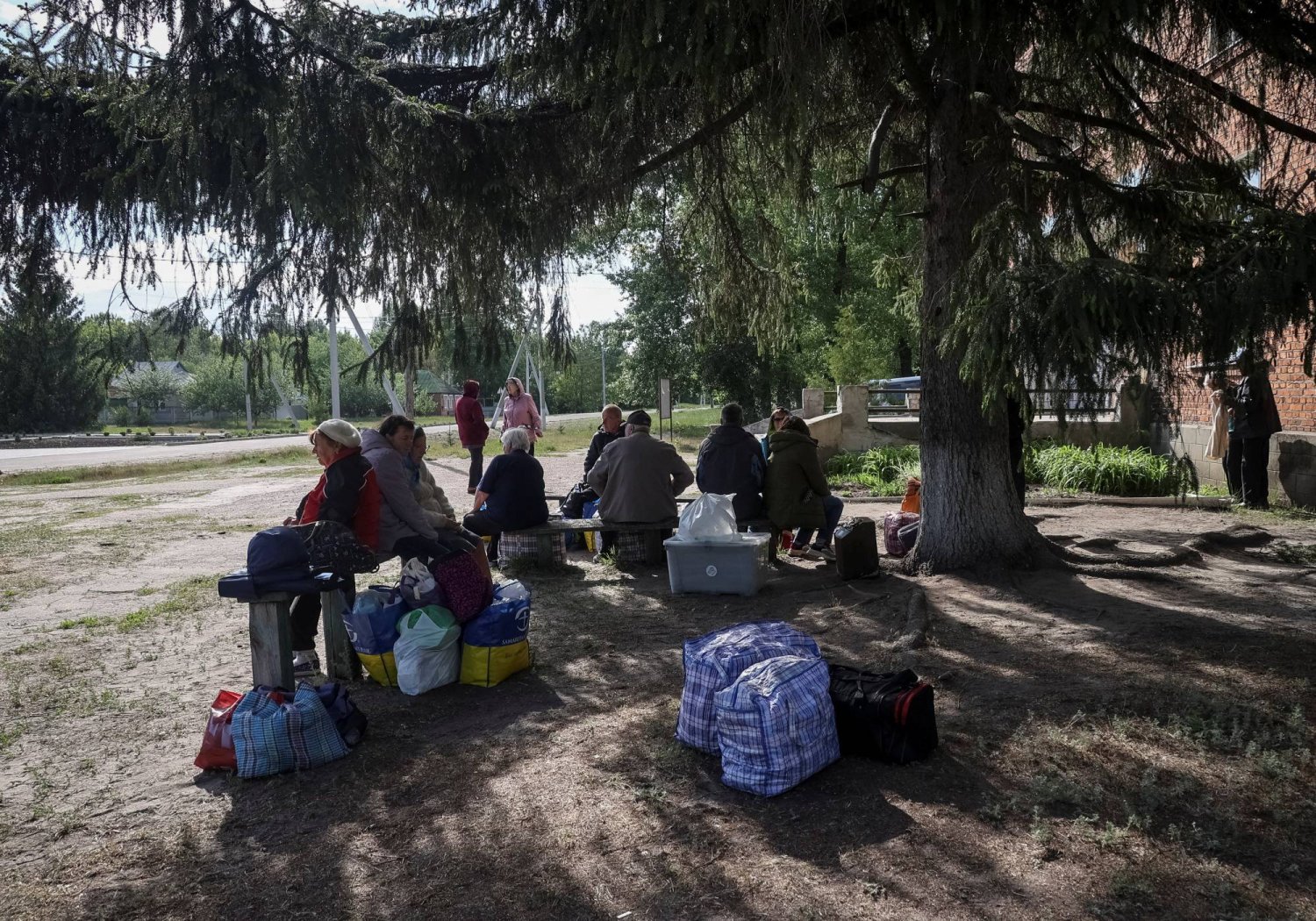 عدد من سكان قرية فوفشانسك في منطقة خاركيف الأوكرانية ينتظرون حافلة لتنقلهم إلى مكان آمن (رويترز)