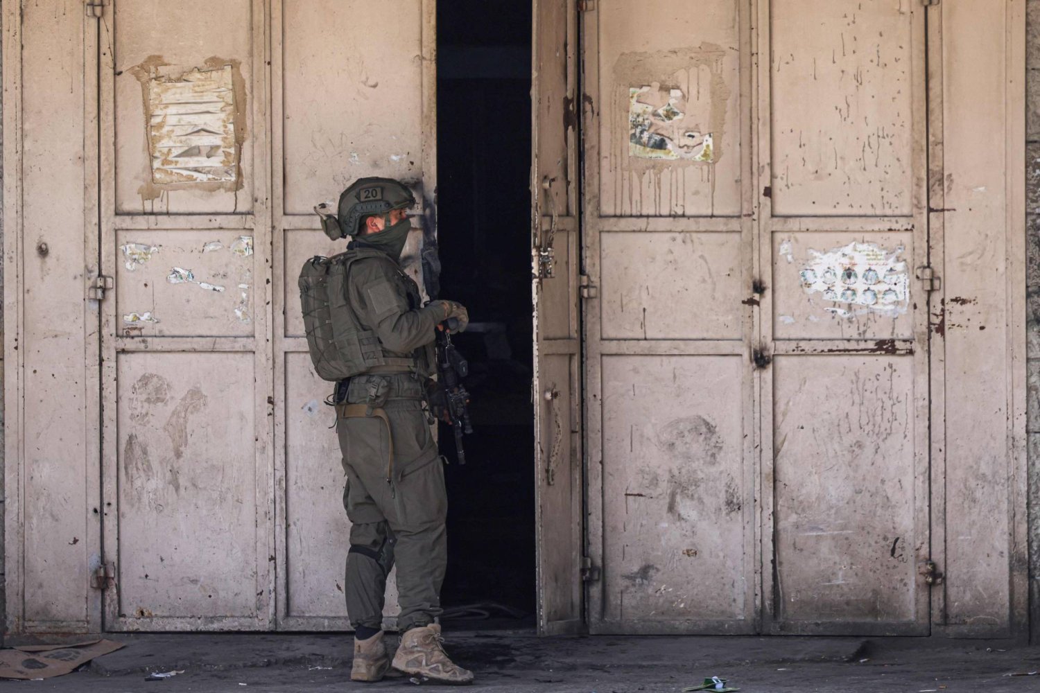 جندي إسرائيلي يقف بجوار متجر خلال مداهمة بلدة طولكرم في الضفة الغربية (أ.ف.ب)