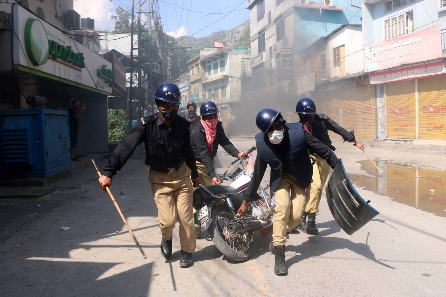 الشرطة الباكستانية تحمل دراجة نارية خلال اشتباكها مع المتظاهرين في احتجاج على اعتقال قادة اللجان والناشطين بمداهمات ليلية في مظفر آباد الأربعاء (إ.ب.أ)