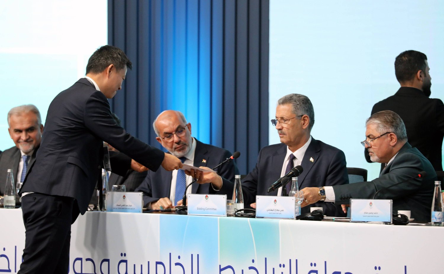 ممثل عن شركة نفط وغاز أجنبية يسلم وثائق عقده إلى وزير النفط العراقي خلال حفل جولة التراخيص السادسة لمشاريع النفط والغاز يوم السبت (إ.ب.أ)