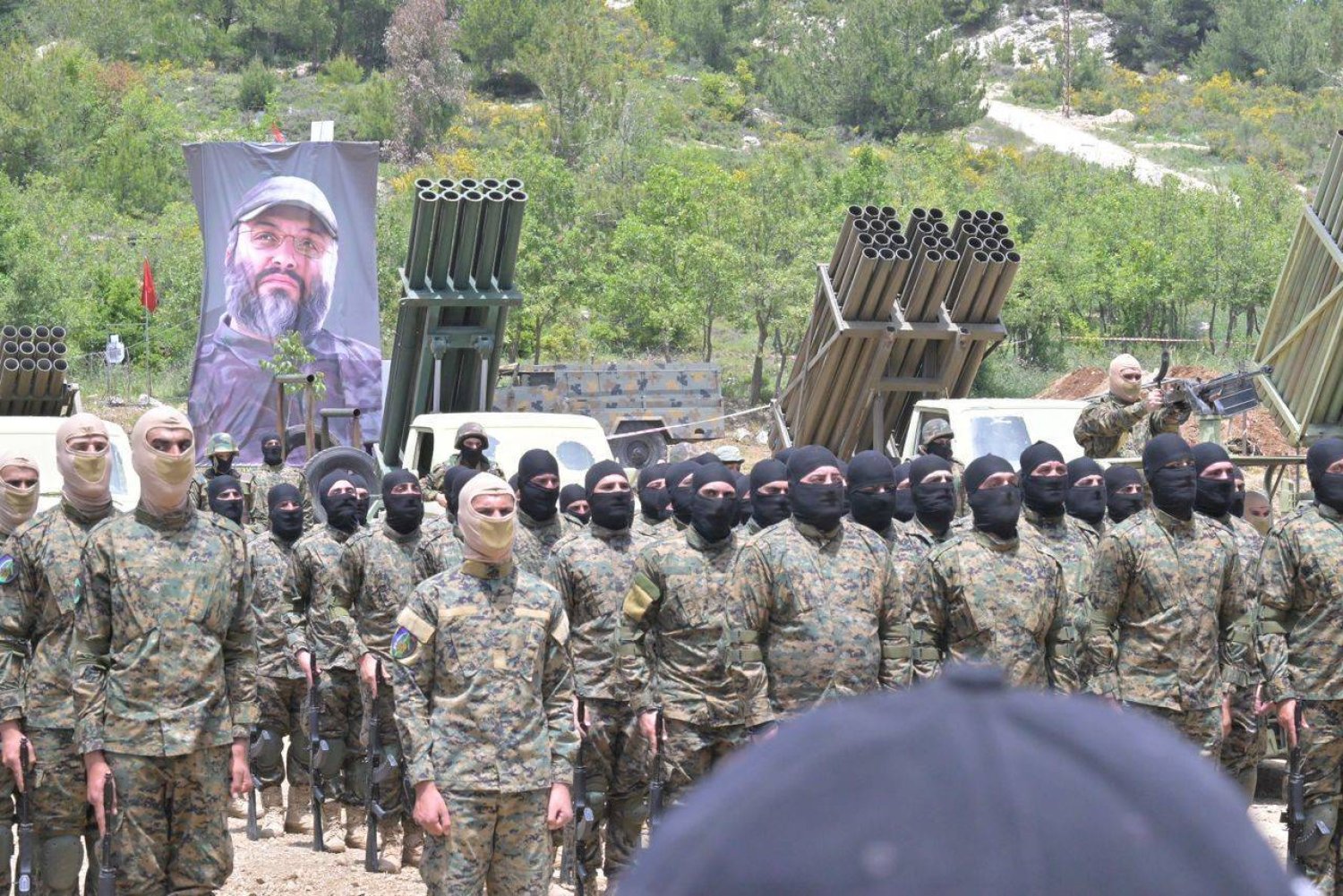 صورة عماد مغنية مرفوعة إلى جانب راجمات صواريخ لـ«حزب الله» خلال مناورة عسكرية بجنوب لبنان العام الماضي (أرشيف «الشرق الأوسط»)