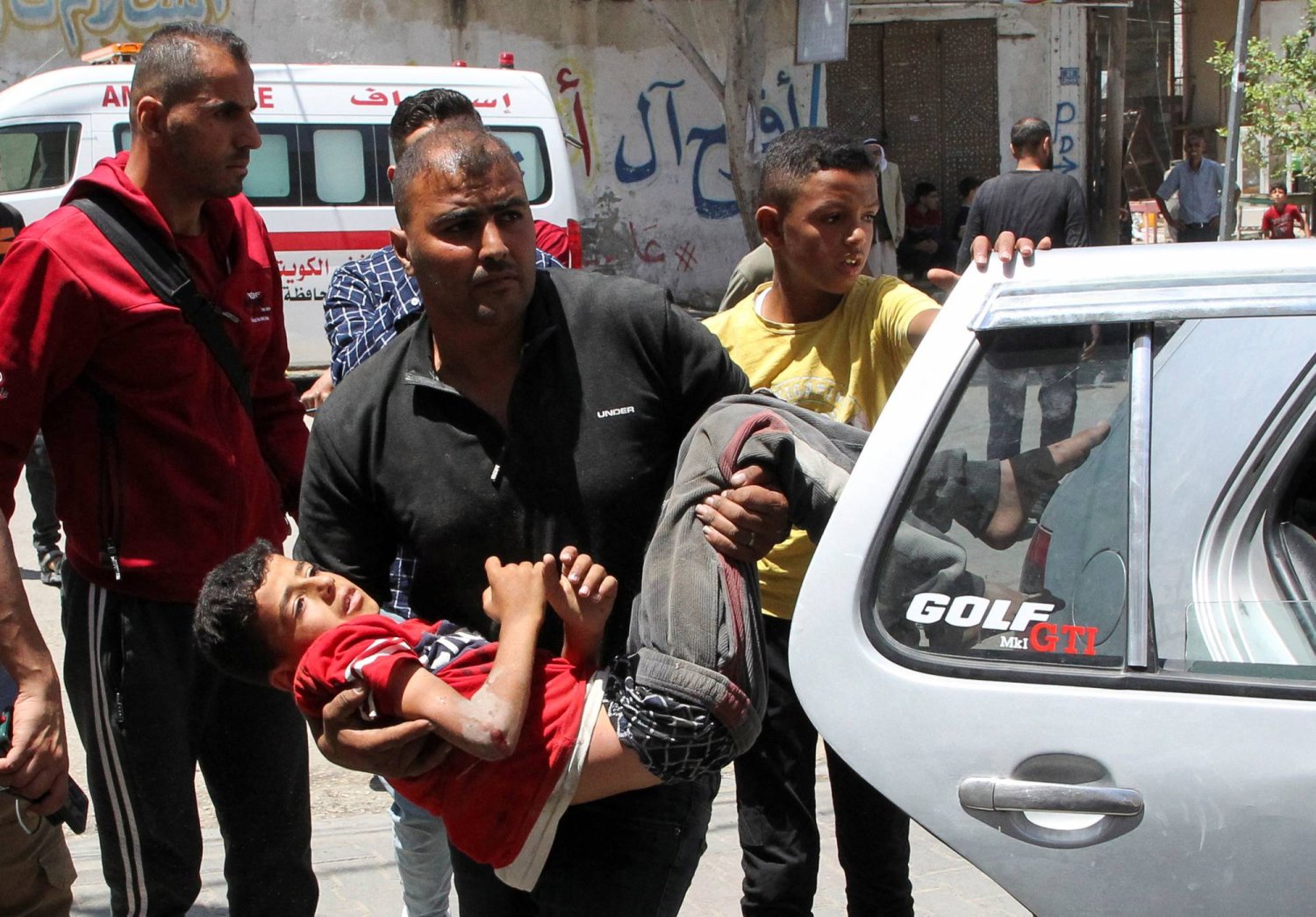 فلسطيني يحمل صبياً أُصيب في غارة إسرائيلية على رفح بجنوب قطاع غزة (رويترز)