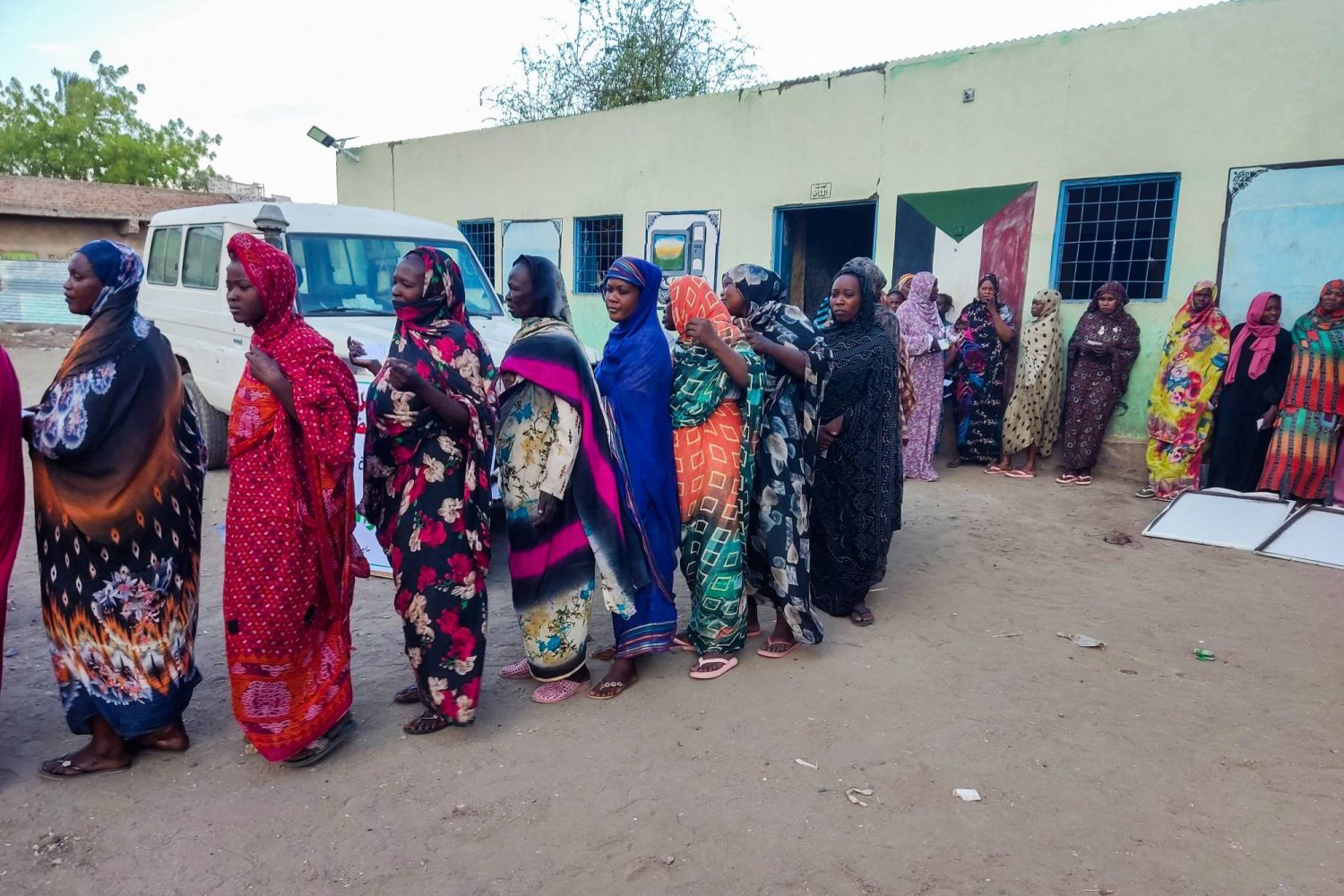 نساء نازحات من دارفور ينتظرن في طابور للحصول على المساعدات من مجموعة في مخيم في القضارف (أ.ف.ب)