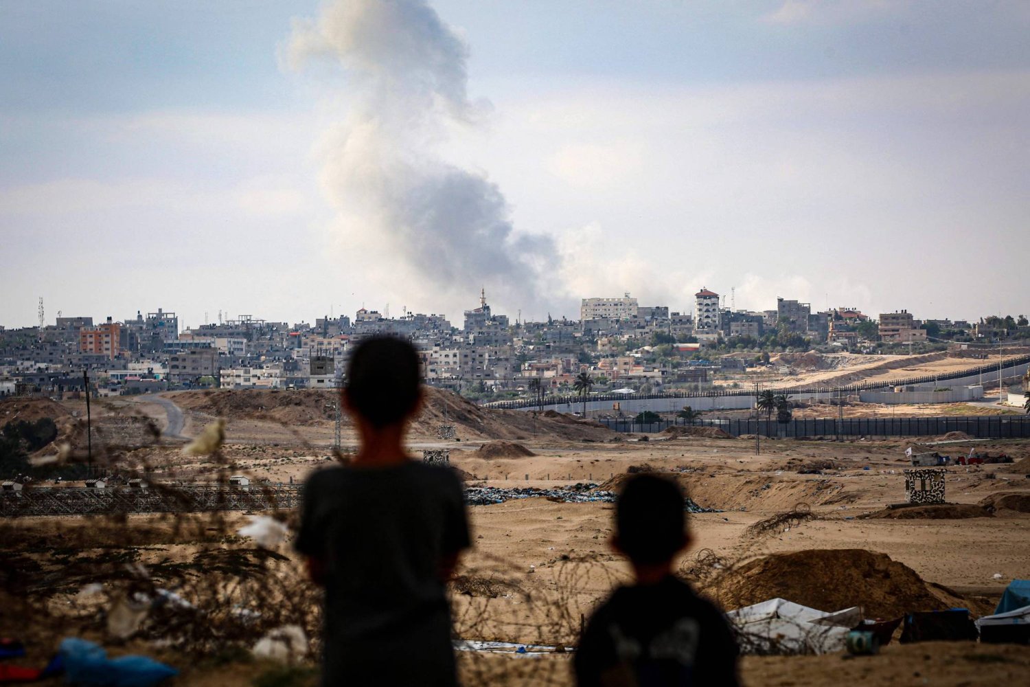 أطفال يشاهدون الدخان يتصاعد خلال الغارات الإسرائيلية شرق رفح في جنوب قطاع غزة (أ.ف.ب)