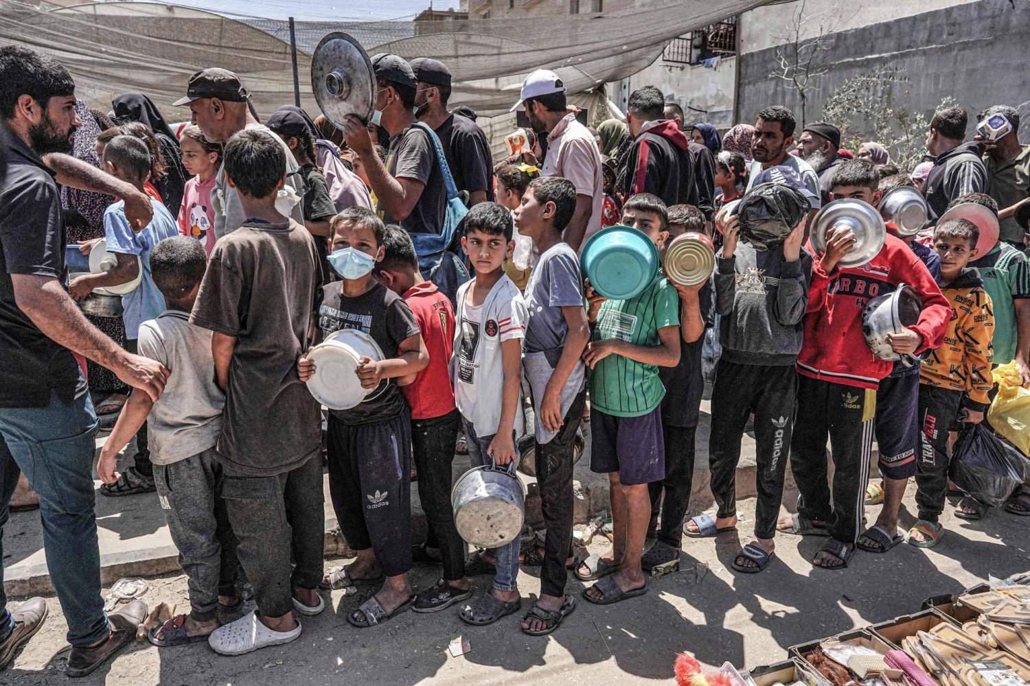 مواطنون ينتظرون في طابور للحصول على مساعدات غذائية في دير البلح الاثنين (أ.ف.ب)
