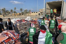 أشخاص يقومون بتحميل قافلة مساعدات إنسانية لقطاع غزة متوقفة في العريش بمصر (إ.ب.أ)