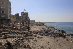 رجل فلسطيني على الشاطئ بالقرب من مبانٍ مدمرة في 29 نوفمبر 2023 في اليوم السادس من وقف إطلاق النار المؤقت بين «حماس» وإسرائيل (أ.ب)