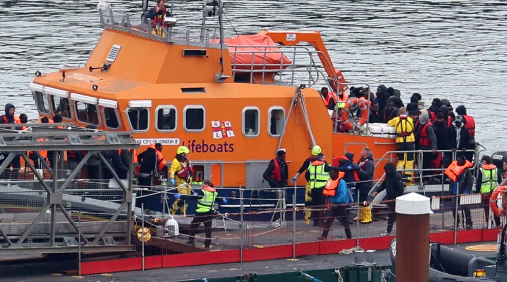 أشخاص يُعتقد أنهم مهاجرون ينزلون من زورق إنقاذ في ميناء دوفر الثلاثاء (رويترز)