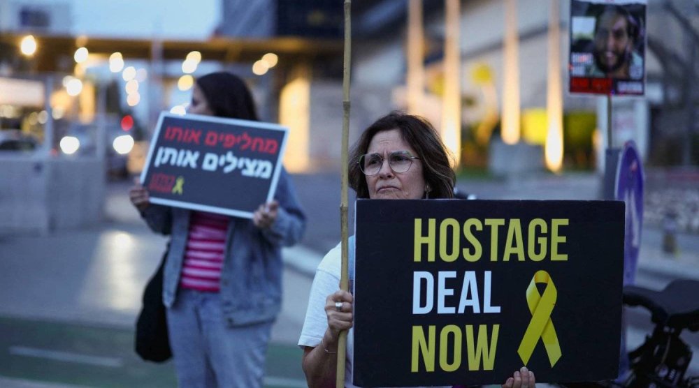متظاهرة تحمل لافتة في تل أبيب تطالب بإبرام صفقة لتحرير المحتجزين في غزة (رويترز)