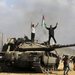 فلسطينيون يحتفلون فوق وحول دبابة إسرائيلية مدمرة قرب سياج قطاع غزة شرق خان يونس أمس (أ.ب)
