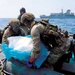 جنديان يحملان بعضاً من الأسلحة الإيرانية المصادرة في خليج عمان الخميس (البحرية الأميركية)