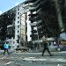 أوكرانيان يسيران أمام بنايات احترقت بفعل القصف في بوروديانكا شمال غربي كييف (أ.ف.ب)