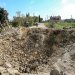 عناصر من الدفاع المدني اللبناني يقفون أمام حفرة في أعقاب غارة جوية إسرائيلية أصابت طريقًا في قرية علما الشعب بجنوب لبنان في 15 أبريل 2024 (أ.ف.ب)