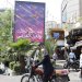 أشخاص يمشون أمام لافتة دعائية تصور صواريخ وطائرات مسيّرة في طهران السبت الماضي (أ.ف.ب)