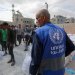أحد موظفي «الأونروا» خلال توزيع أجولة الطحين على النازحين في غزة (حساب «الأونروا» على «إكس»)