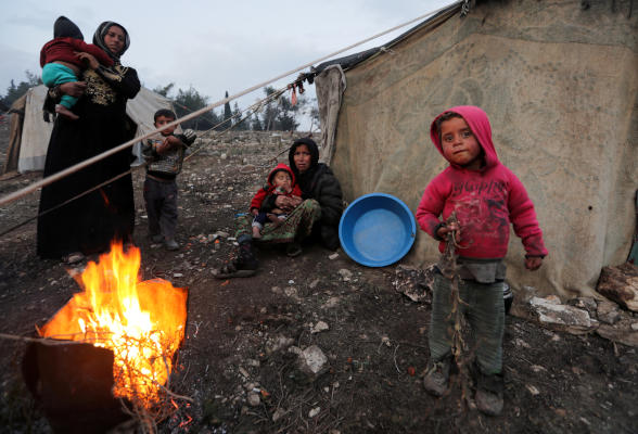 سيدات وأطفال نزحوا من جنوب إدلب أوقدوا نارا للتدفئة في عفرين (رويترز)